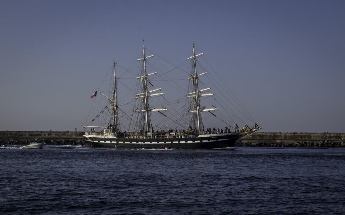 A tall sailing ship on the open ocean under a clear sky